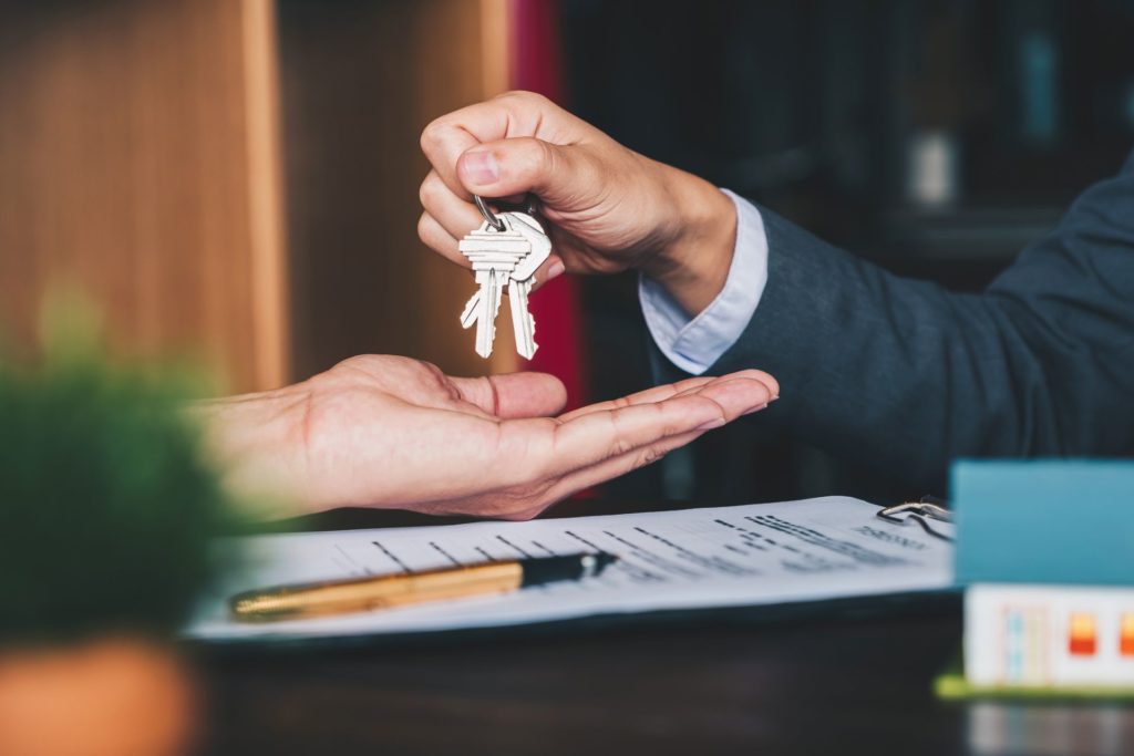 A picture of two people's hands exchanging keys and contracts
